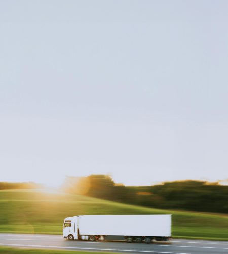 White cargo truck speeding through Vitebsk countryside at sunrise, symbolizing transportation and logistics.